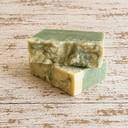 Two green soap bars stacked on a wooden surface