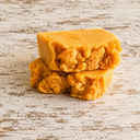 Two pieces of turmeric soap stacked on a wooden surface