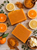 Orange soap bars with citrus fruits and spices on a wooden surface